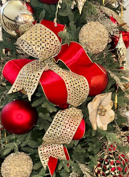 Red ornaments and gold mesh ribbon bows on a full green tree